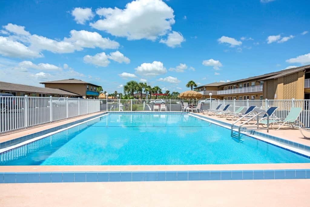 An outdoor swimming pool surrounded by a white fence and lounge chairs at a motel — 4651 W IRLO BRONSON MEMORIAL HIGHWAY, KISSIMMEE, FL