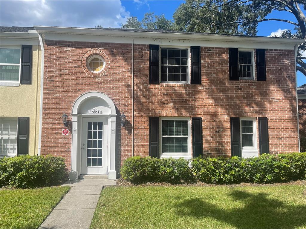A two-story brick townhouse features a white arched front door and black window shutters — 13831 ORANGE SUNSET DRIVE UNIT 201, TAMPA, FL