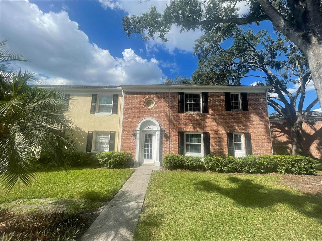 A two-story townhouse with a brick and stucco facade, black shutters, and a front walkway — 13831 ORANGE SUNSET DRIVE UNIT 201, TAMPA, FL