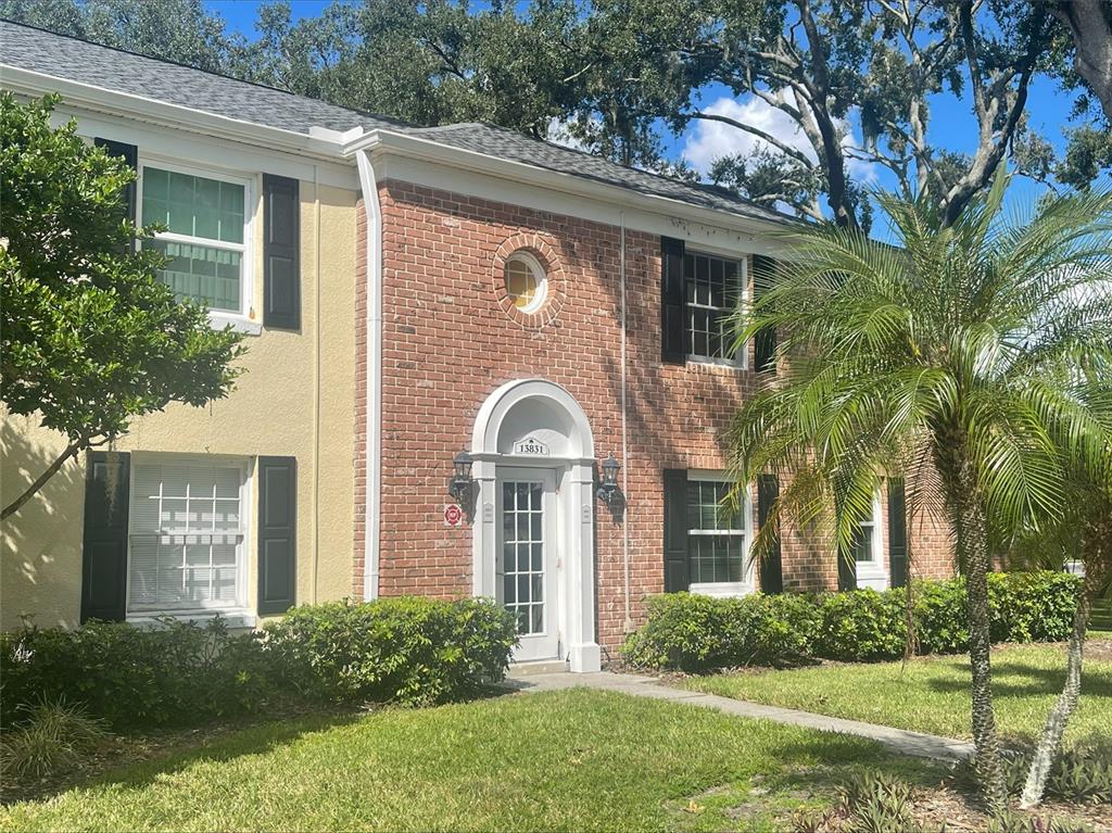 A two-story brick and stucco townhouse with black shutters and a white arched entryway — 13831 ORANGE SUNSET DRIVE UNIT 201, TAMPA, FL