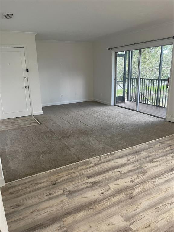 An empty living room features gray carpeting, light wood-look flooring, and a sliding glass door — 13831 ORANGE SUNSET DRIVE UNIT 201, TAMPA, FL