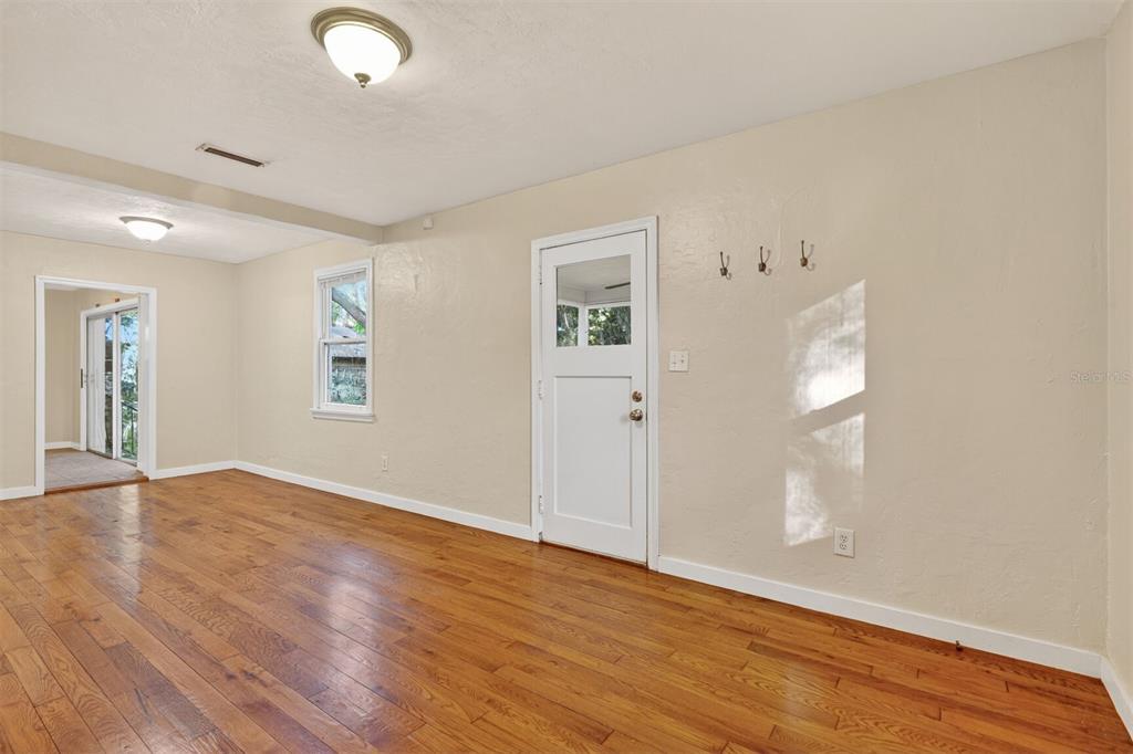 An interior room with hardwood floors, a white door, and a window on beige walls — 914 NE 6TH AVENUE, GAINESVILLE, FL