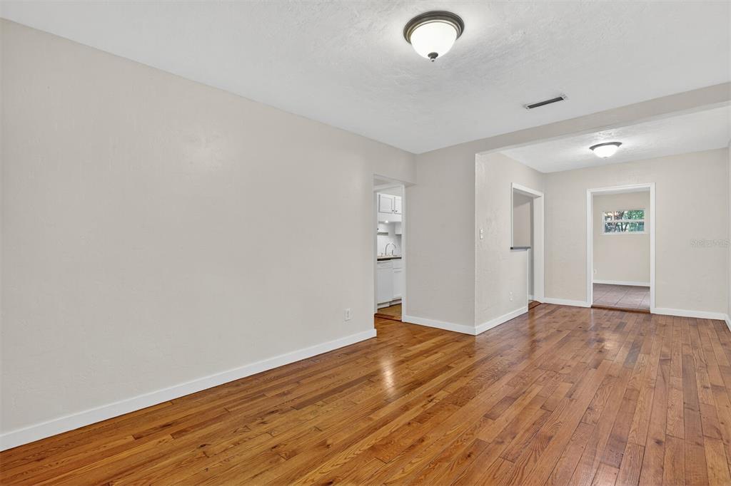 An empty room with light-colored walls, hardwood flooring, and two ceiling light fixtures — 914 NE 6TH AVENUE, GAINESVILLE, FL