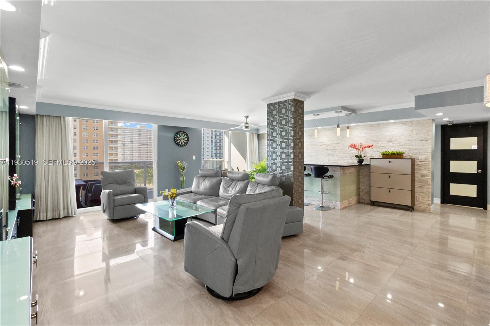 A modern living room features gray leather furniture, a glass coffee table, and a bar area — 1880 S Ocean Dr, Hallandale Beach FL 33009, HALLANDALE BEACH, FL