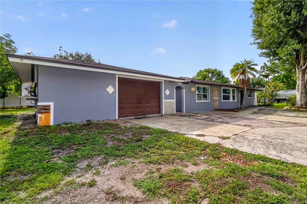 A gray single-story house features a brown garage door, concrete driveway, and a palm tree — 4734 DELMONTE AVENUE, SARASOTA, FL