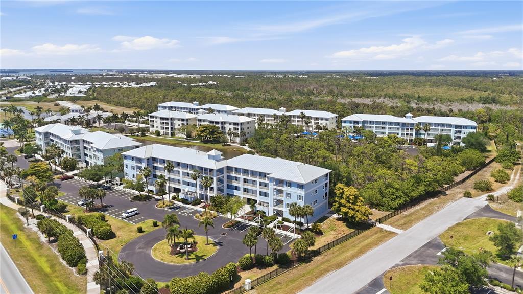 An aerial view shows multi-story apartment buildings surrounded by parking lots and wooded areas — 8405 PLACIDA ROAD UNIT 204, PLACIDA, FL