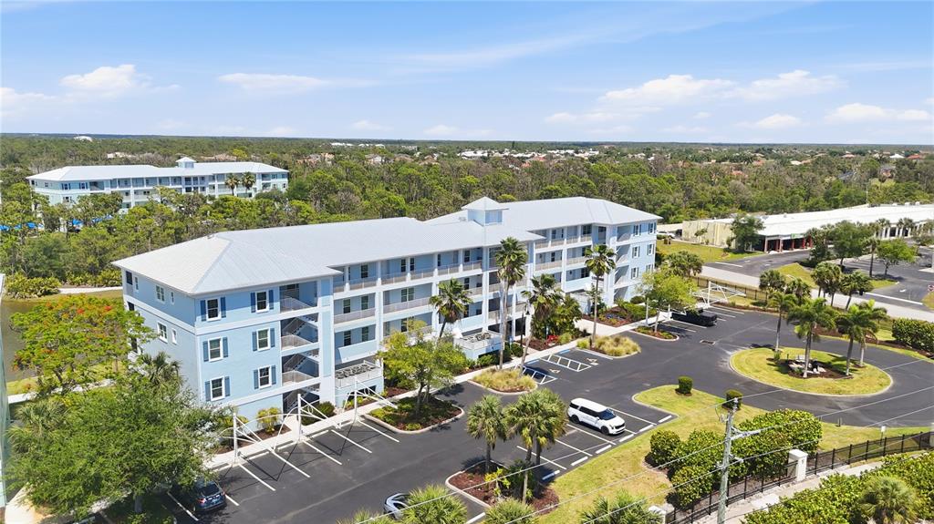 An aerial view shows a multi-story blue apartment building with a parking lot — 8405 PLACIDA ROAD UNIT 204, PLACIDA, FL