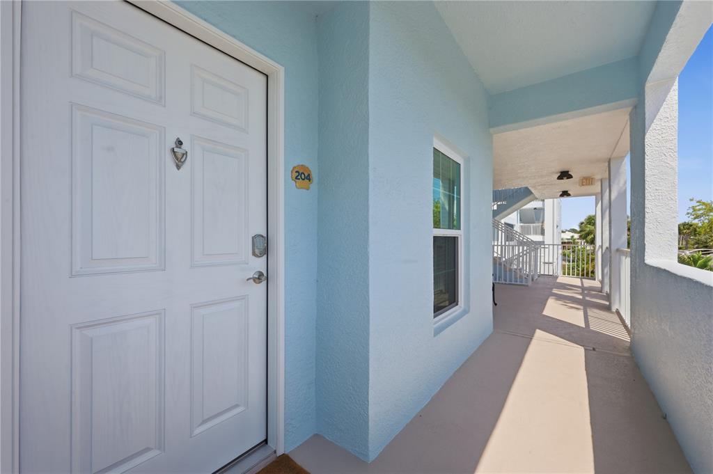 A white front door with a number 204 plaque opens onto a light blue exterior hallway — 8405 PLACIDA ROAD UNIT 204, PLACIDA, FL