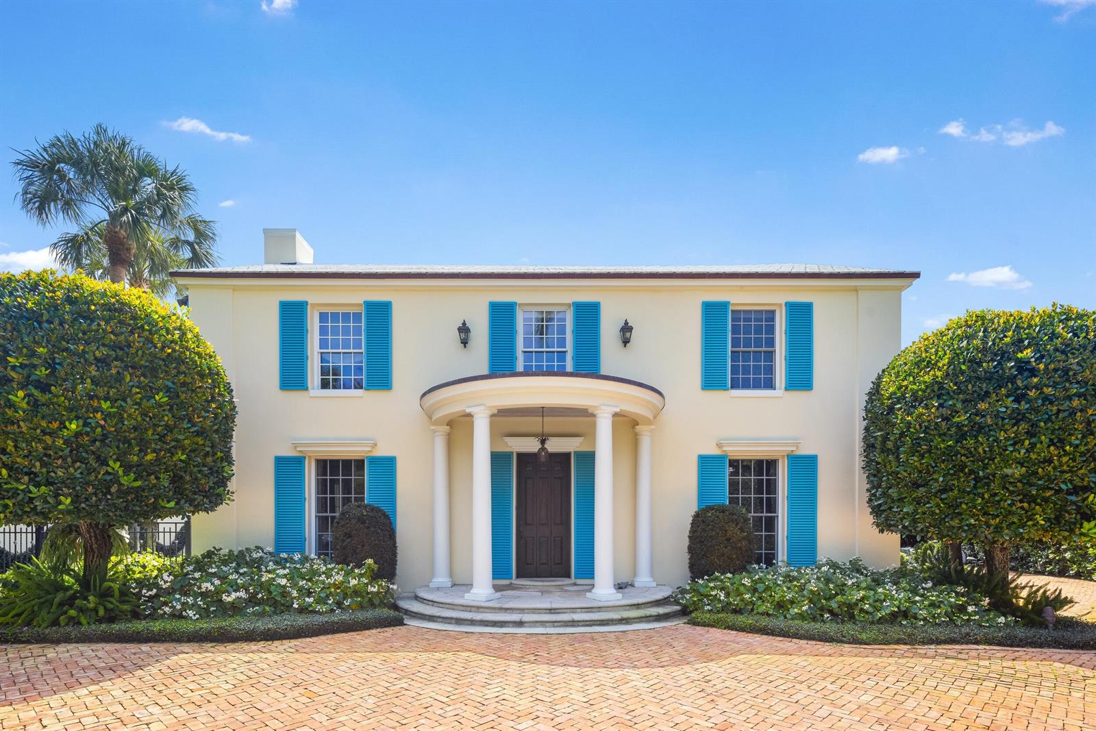 A two-story cream-colored house features a circular portico, blue shutters, and a brick driveway — 246 Emerald Lane, Palm Beach FL 33480, PALM BEACH, FL