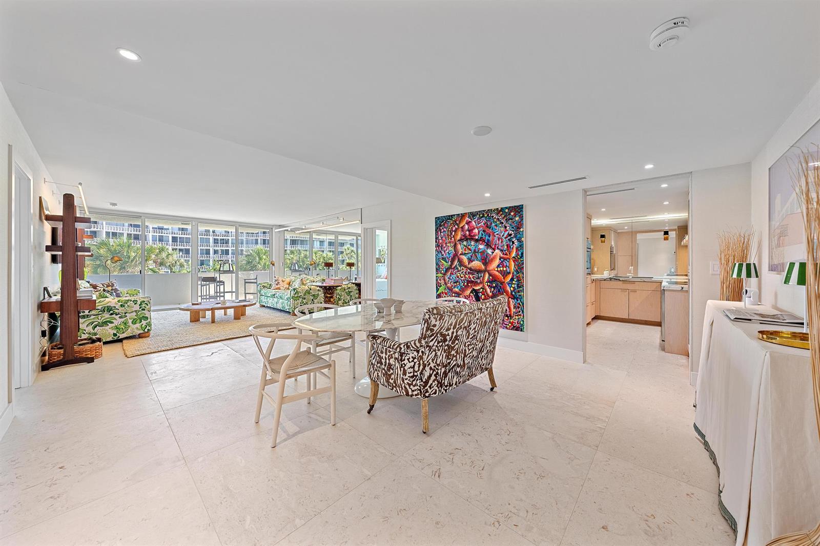 A bright living and dining area with marble floors, colorful art, and a balcony view — 2773 S Ocean Boulevard # 209, Palm Beach FL 33480, PALM BEACH, FL