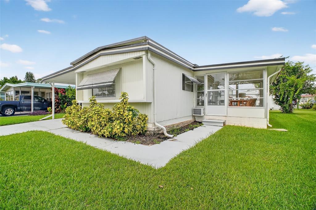 A light-colored mobile home with a screened-in porch, metal awning, and a concrete driveway — 227 PARADISE S, LEESBURG, FL