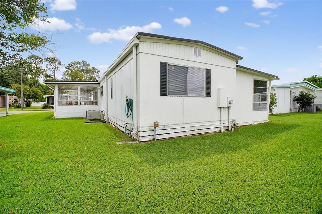 The exterior of a white manufactured home features a screened-in porch and a grassy yard — 227 PARADISE S, LEESBURG, FL