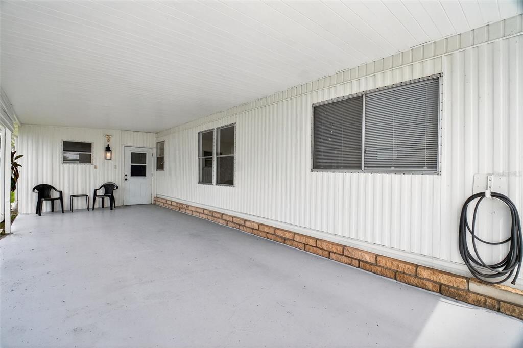 A covered carport features white corrugated metal siding, a brick base, and a concrete floor — 227 PARADISE S, LEESBURG, FL