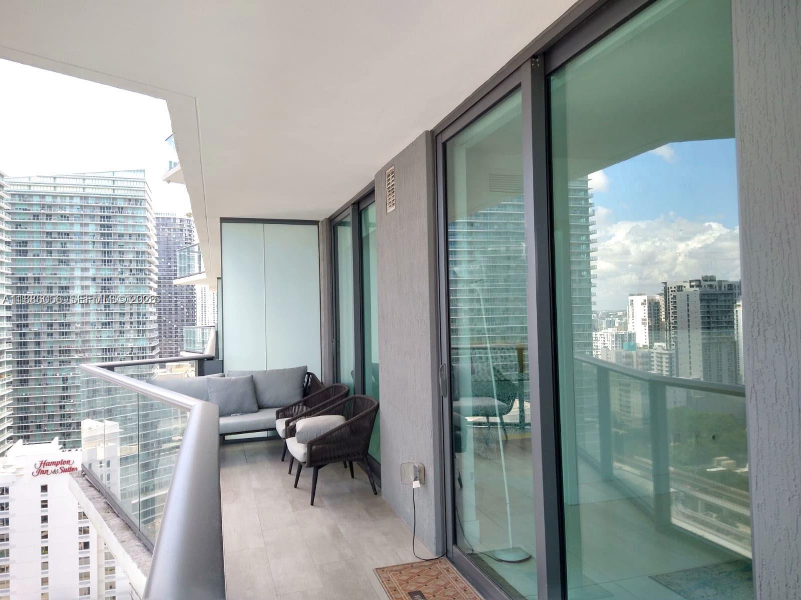 A balcony with gray furniture overlooks a cityscape with high-rise buildings — 1300 S Miami Ave # 2208, Miami FL 33130, MIAMI, FL