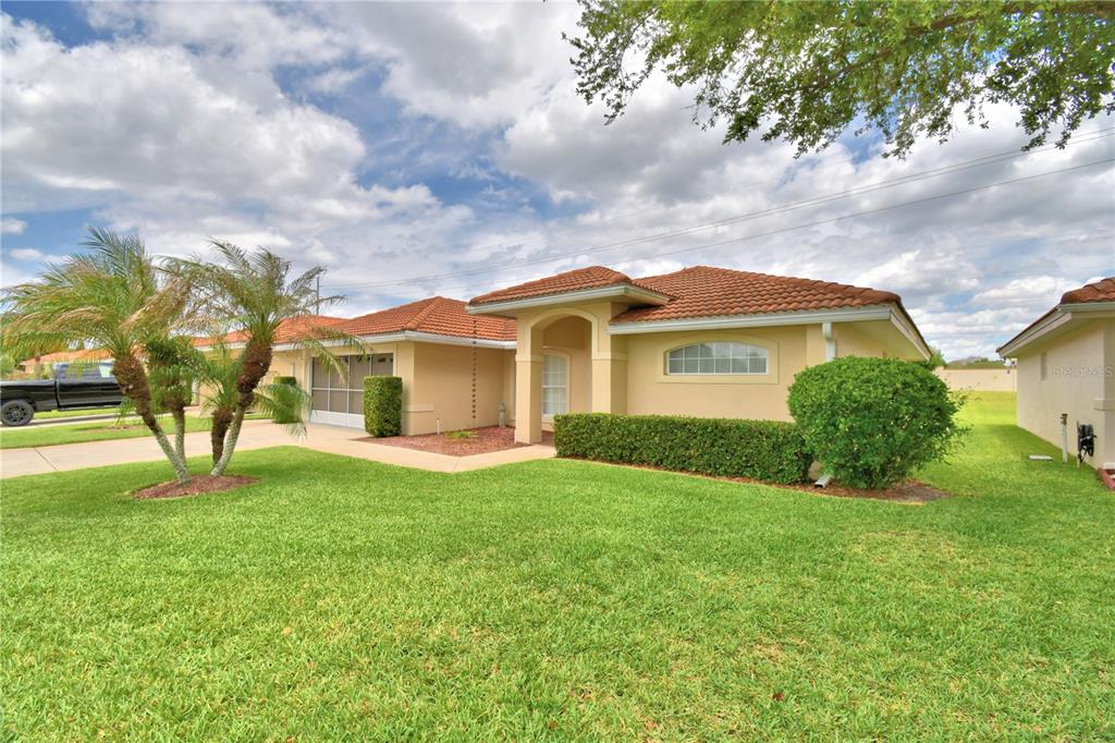 A single-story house with a tan stucco exterior, a tiled roof, and a front lawn — 142 MORNING GLORY CIRCLE, WINTER HAVEN, FL