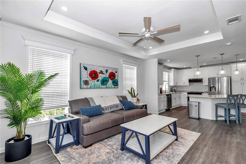 A living room with a grey sofa and coffee table opens into a white kitchen — 521 NW 80TH AVENUE, OCALA, FL