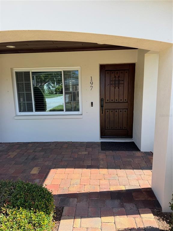 A paved walkway leads to a front door with a decorative window and house number — 197 IRWIN STREET W, SAFETY HARBOR, FL