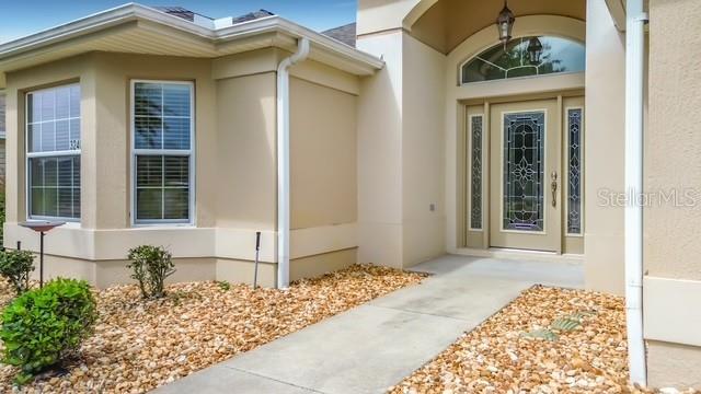 The exterior of a beige house features a front door with decorative glass and windows — 3240 LAFAYETTE STREET, THE VILLAGES, FL