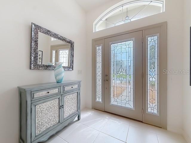 An entryway features a blue cabinet, a decorative mirror, and a front door with glass panels — 3240 LAFAYETTE STREET, THE VILLAGES, FL