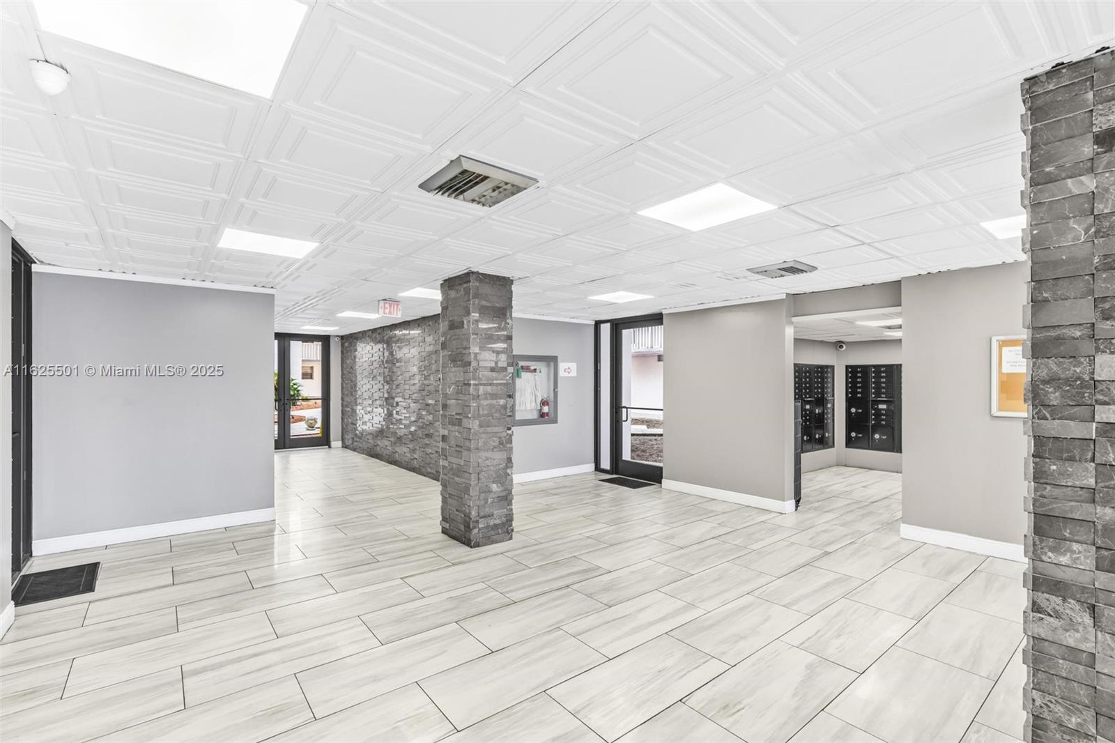 A modern lobby features gray tile flooring, stone-accented pillars, and a white coffered ceiling — 15600 NW 7th Ave # 306, Miami FL 33169, MIAMI, FL