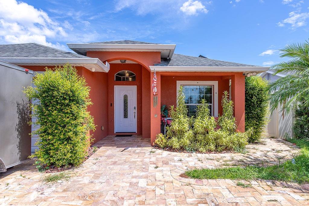 The exterior of a single-story house features orange stucco walls, a white front door, and pavers — 4907 CARLYLE ROAD, TAMPA, FL