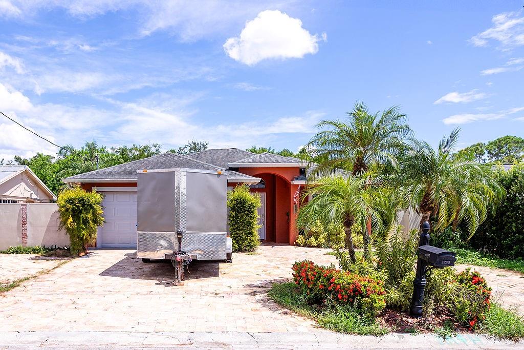 A single-story house with a paved driveway, a parked trailer, and palm trees in front — 4907 CARLYLE ROAD, TAMPA, FL
