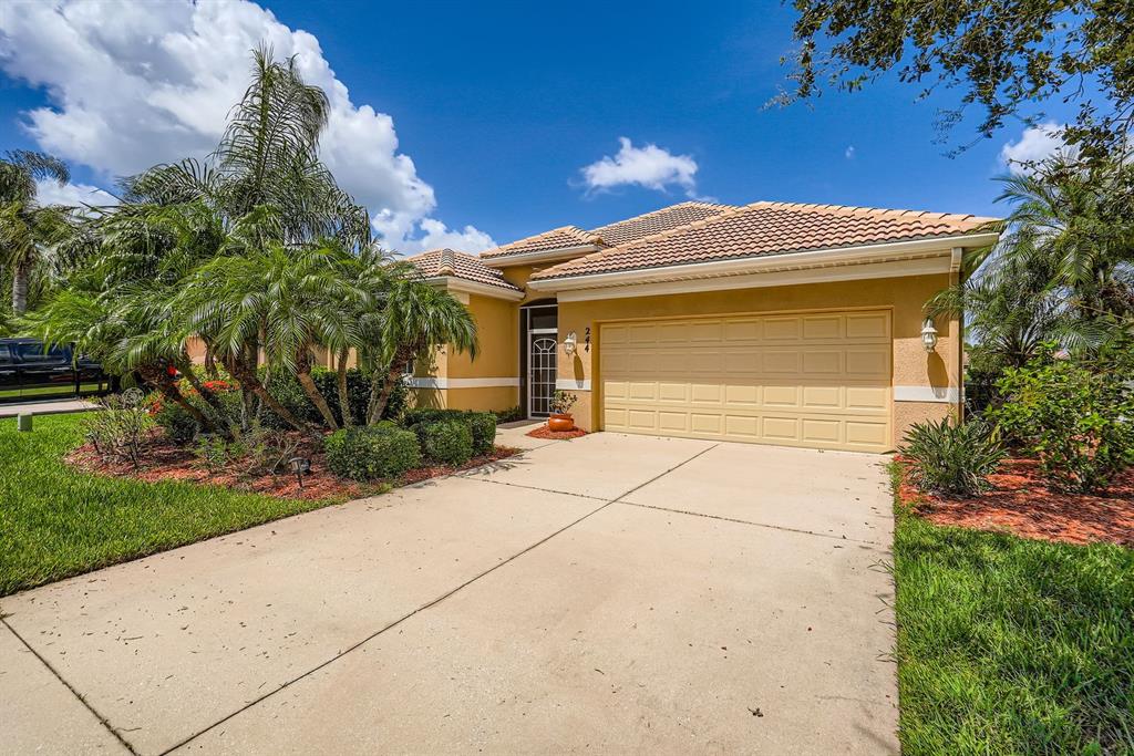 A single-story house with a tan stucco exterior, a two-car garage, and palm trees — 244 GOLDEN HARBOUR TRAIL, BRADENTON, FL