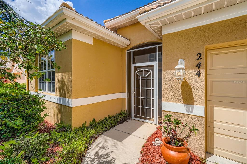 The exterior of a yellow stucco house features a screen door and a garage — 244 GOLDEN HARBOUR TRAIL, BRADENTON, FL