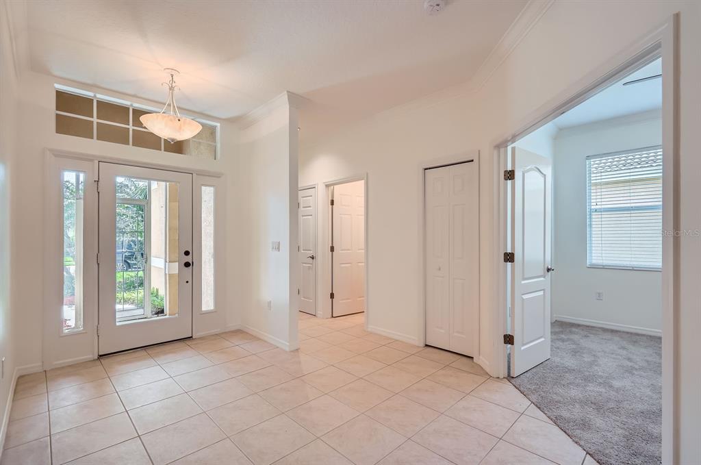 A tiled entryway features a front door with sidelights, a chandelier, and interior doorways — 244 GOLDEN HARBOUR TRAIL, BRADENTON, FL