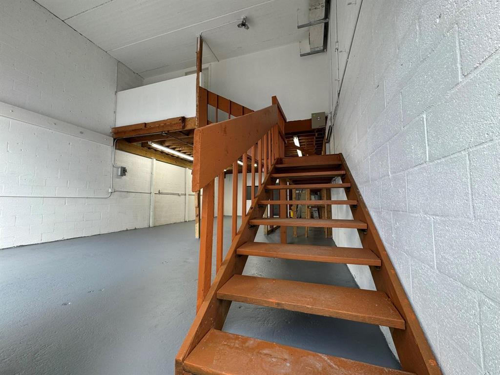 A wooden staircase leads to a loft area in an industrial space with concrete walls — 1773 Blount Road # 313, Pompano Beach FL 33069, POMPANO BEACH, FL