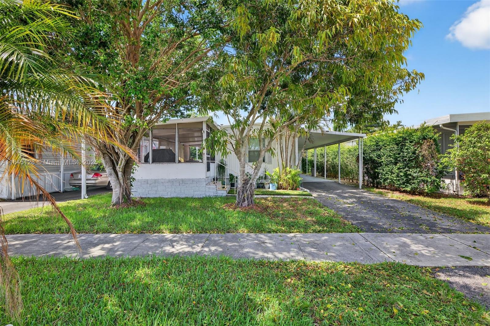 A single-story mobile home with a screened porch, carport, and mature trees in the front yard — 2430 SW 53rd St, Dania Beach FL 33312, DANIA BEACH, FL