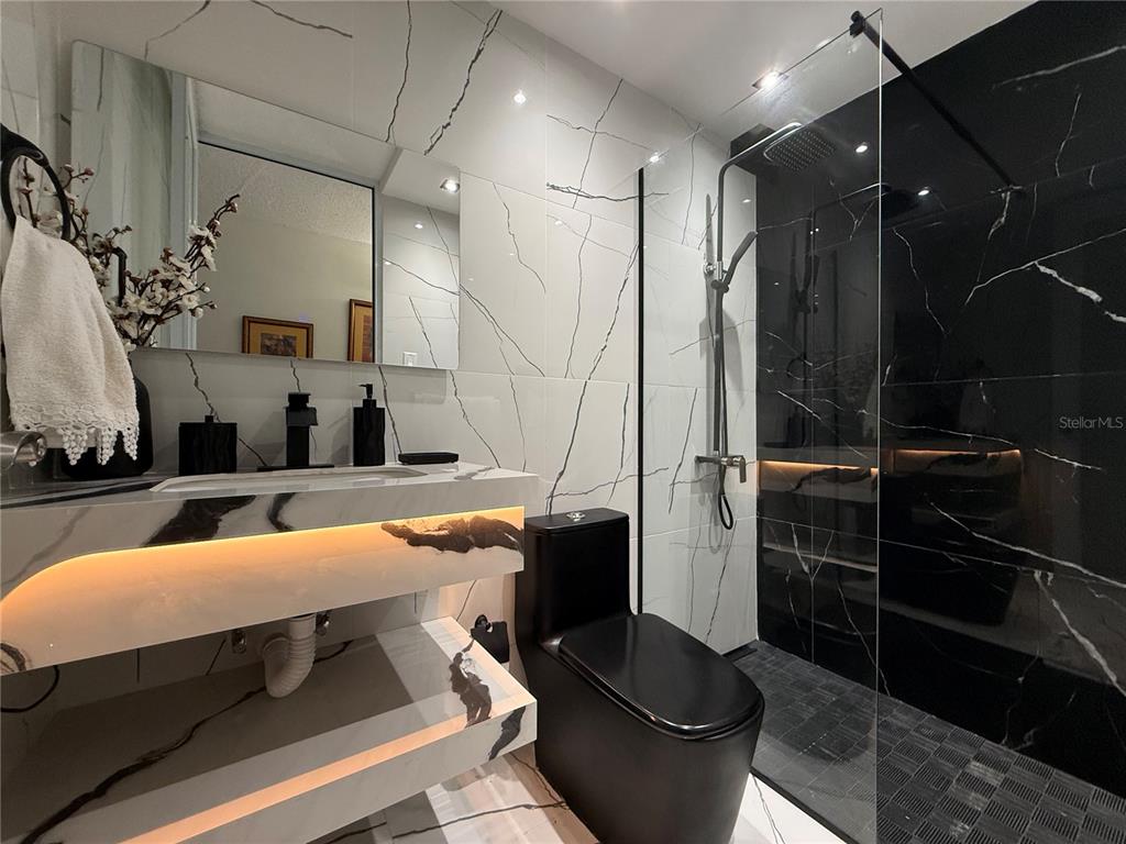 A modern bathroom features a floating marble vanity, a black toilet, and a glass-enclosed shower — 57 LOPATEGUI UNIT BB-2, GUAYNABO, PR