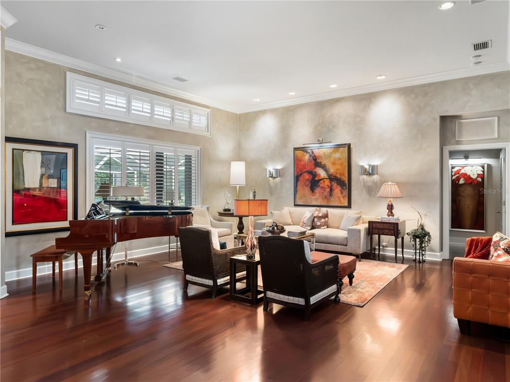 A living room features a grand piano, hardwood floors, neutral walls, and multiple seating areas — 16211 VILLARREAL DE AVILA, TAMPA, FL