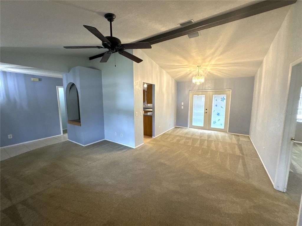 A carpeted living room features a ceiling fan, vaulted ceilings, and French doors — 2089 WINNINGWAY STREET, PORT CHARLOTTE, FL