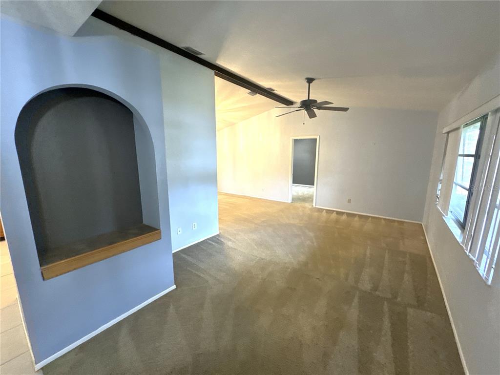 A living room with light blue walls, beige carpet, a ceiling fan, and an arched niche — 2089 WINNINGWAY STREET, PORT CHARLOTTE, FL