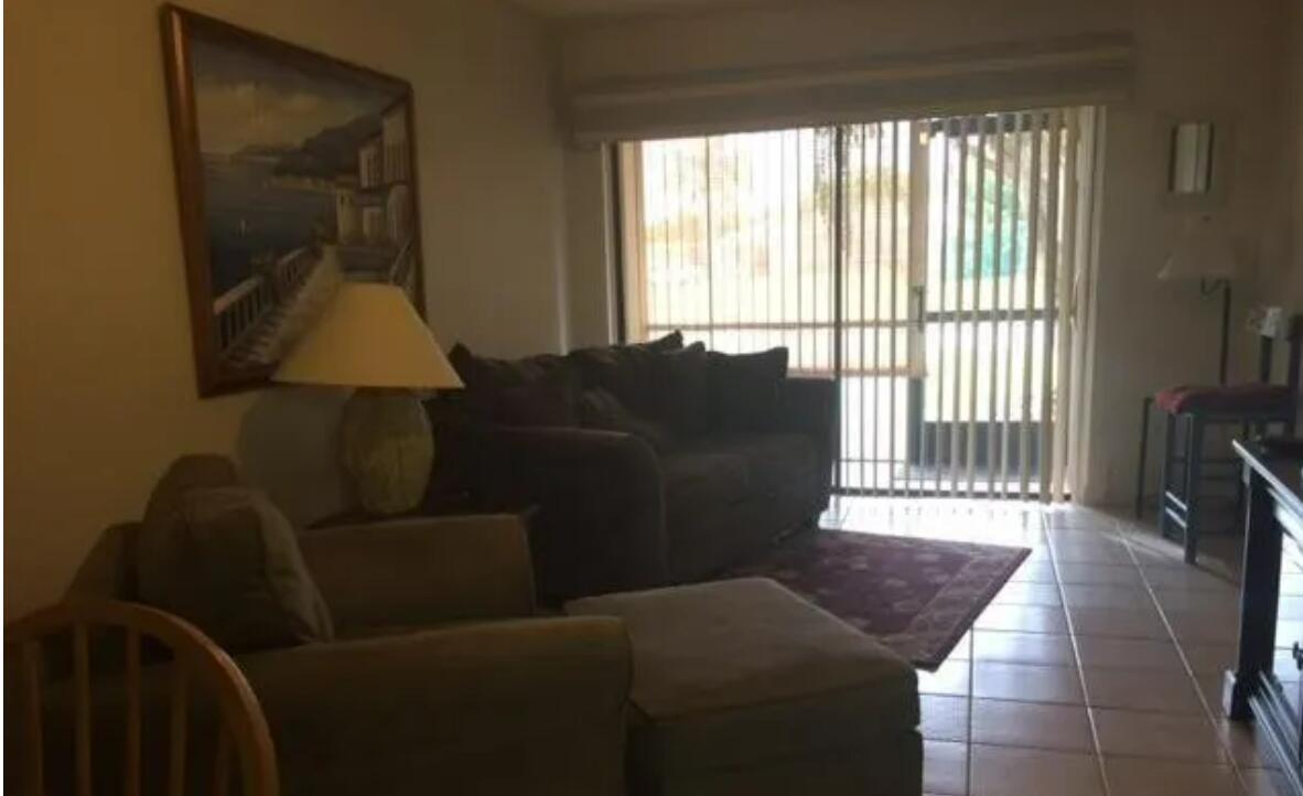 A living room features a dark sofa, an armchair with an ottoman, and tile flooring — 1971 NE Collins Circle # 20, Jensen Beach FL 34957, JENSEN BEACH, FL
