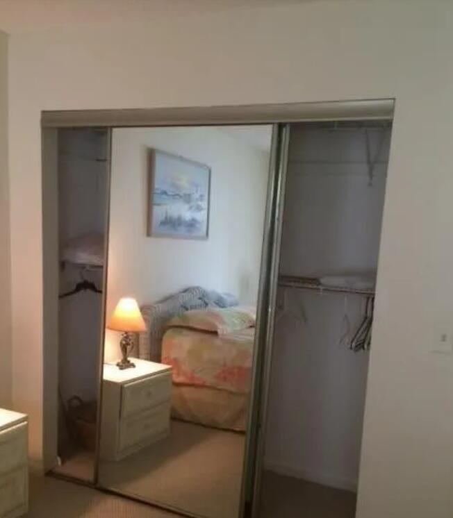 A bedroom closet features sliding mirrored doors reflecting a bed and a bedside lamp — 1971 NE Collins Circle # 20, Jensen Beach FL 34957, JENSEN BEACH, FL