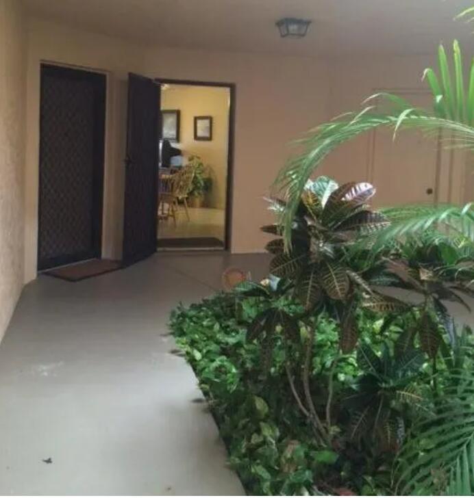 An exterior entryway features a dark screen door, a view into a room, and landscaping — 1971 NE Collins Circle # 20, Jensen Beach FL 34957, JENSEN BEACH, FL