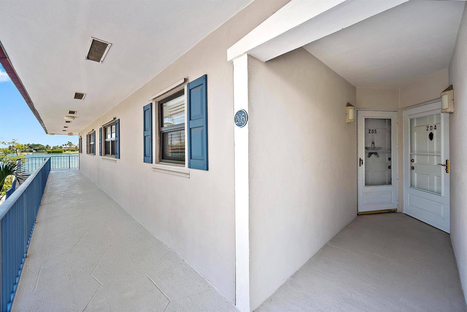 An outdoor walkway with blue railings leads to apartment doors numbered 204 and 205 — 755 Saturn D205 Street # D205, Jupiter FL 33477, JUPITER, FL