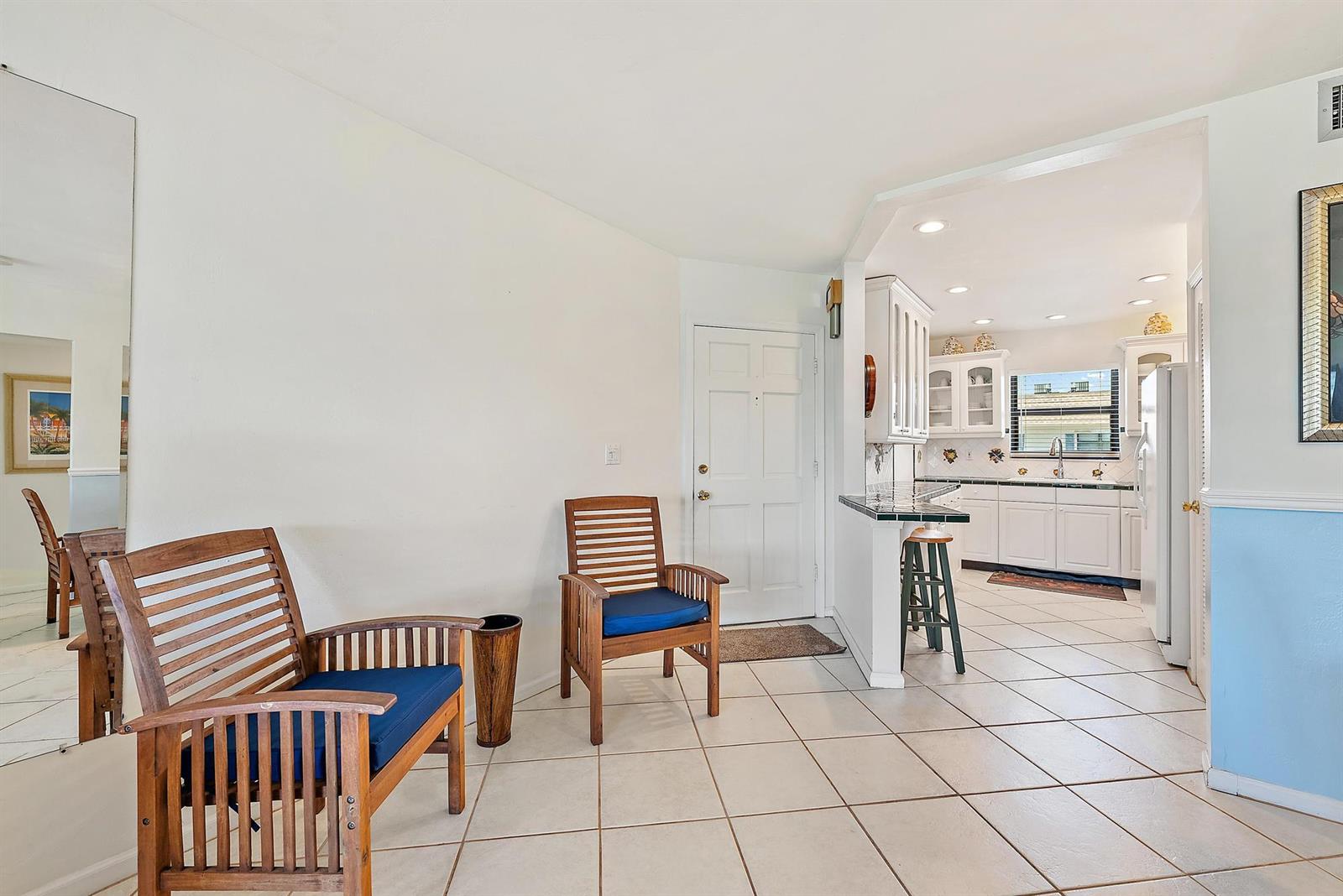 A tiled entryway leads to a kitchen with white cabinets and a breakfast bar — 755 Saturn D205 Street # D205, Jupiter FL 33477, JUPITER, FL