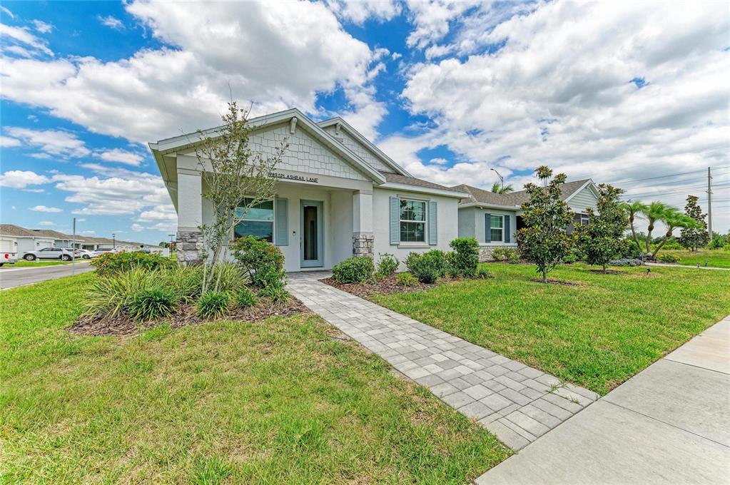 A single-story house with a stone-accented porch and a paved walkway in a suburban neighborhood — 1989 SPLASHRAIL LANE, SARASOTA, FL