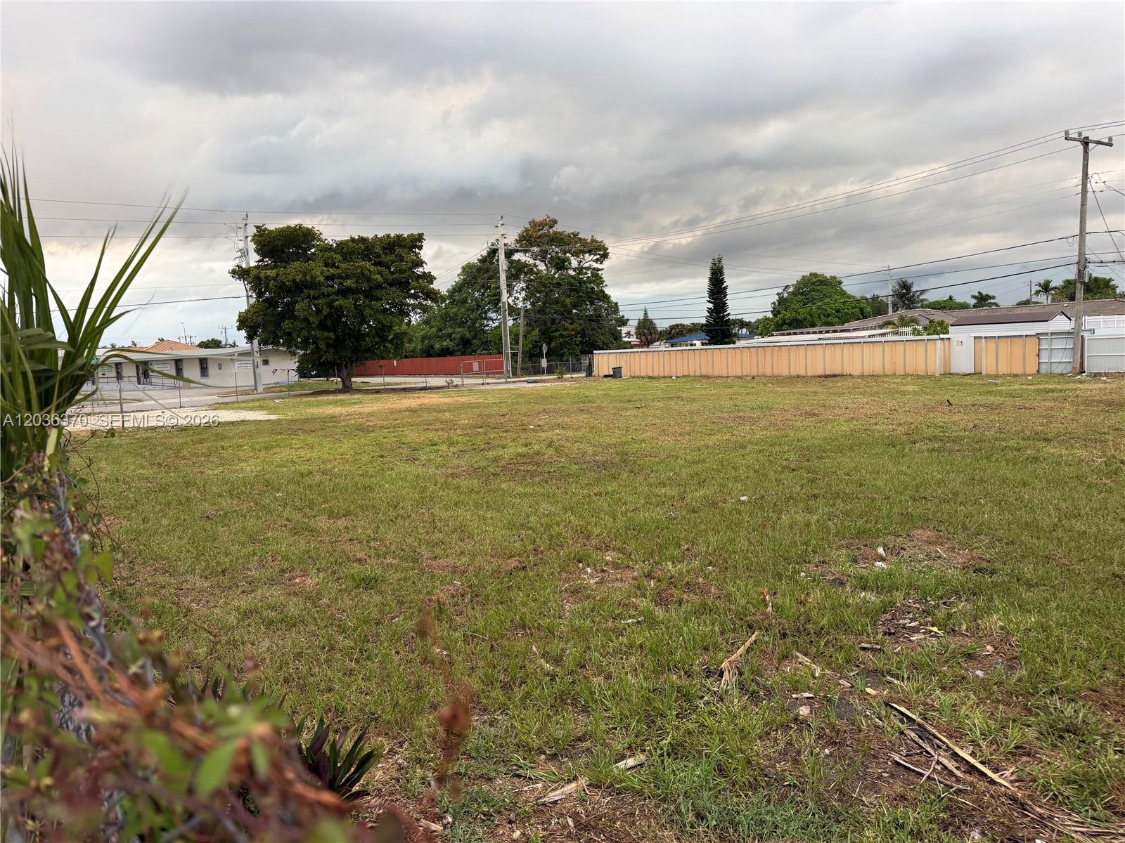 A vacant, grassy lot is enclosed by a fence under a cloudy sky — 291 W 49th St, Hialeah FL 33012, HIALEAH, FL