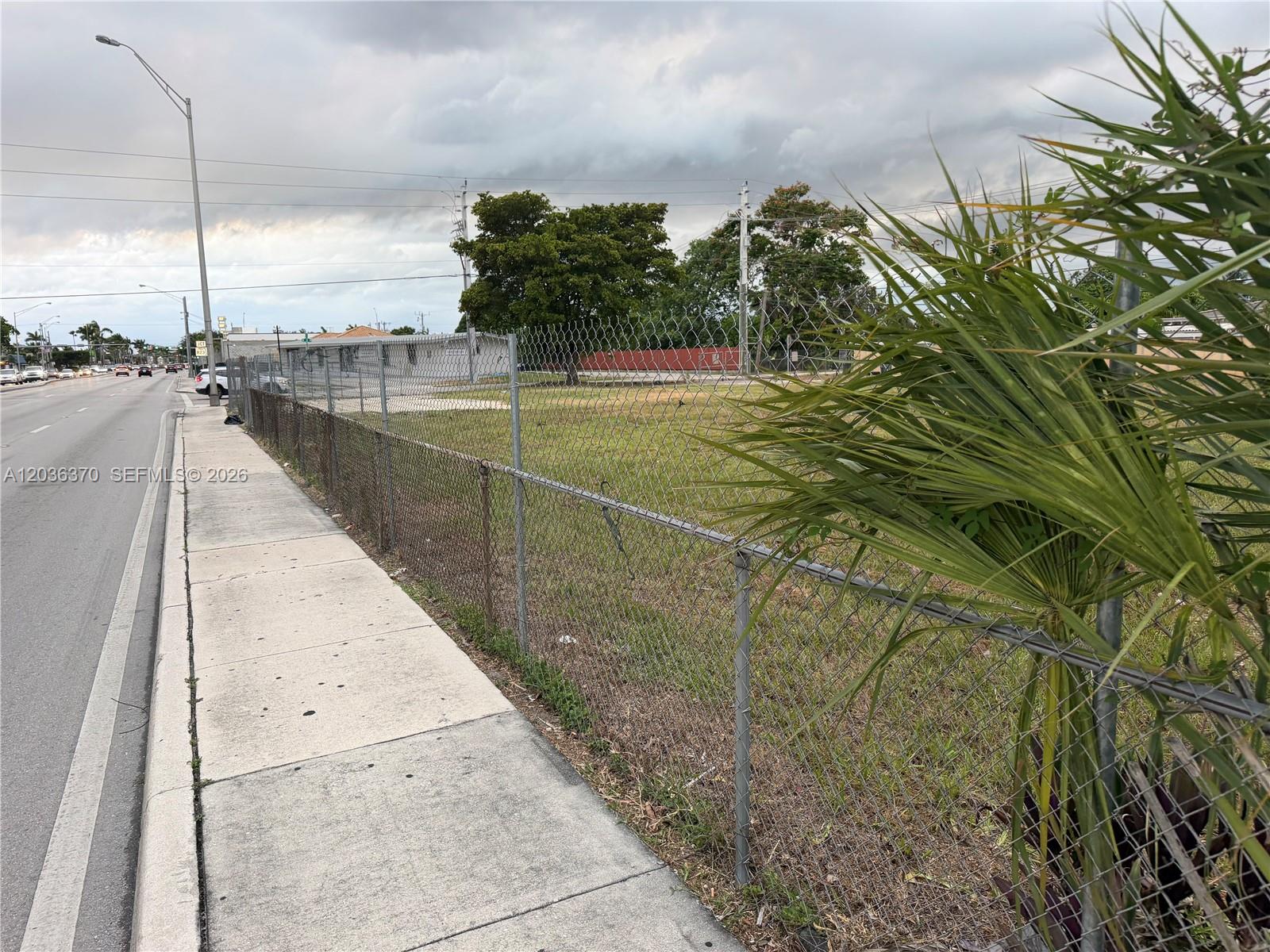 A chain-link fence borders a vacant grassy lot next to a sidewalk and road — 291 W 49th St, Hialeah FL 33012, HIALEAH, FL