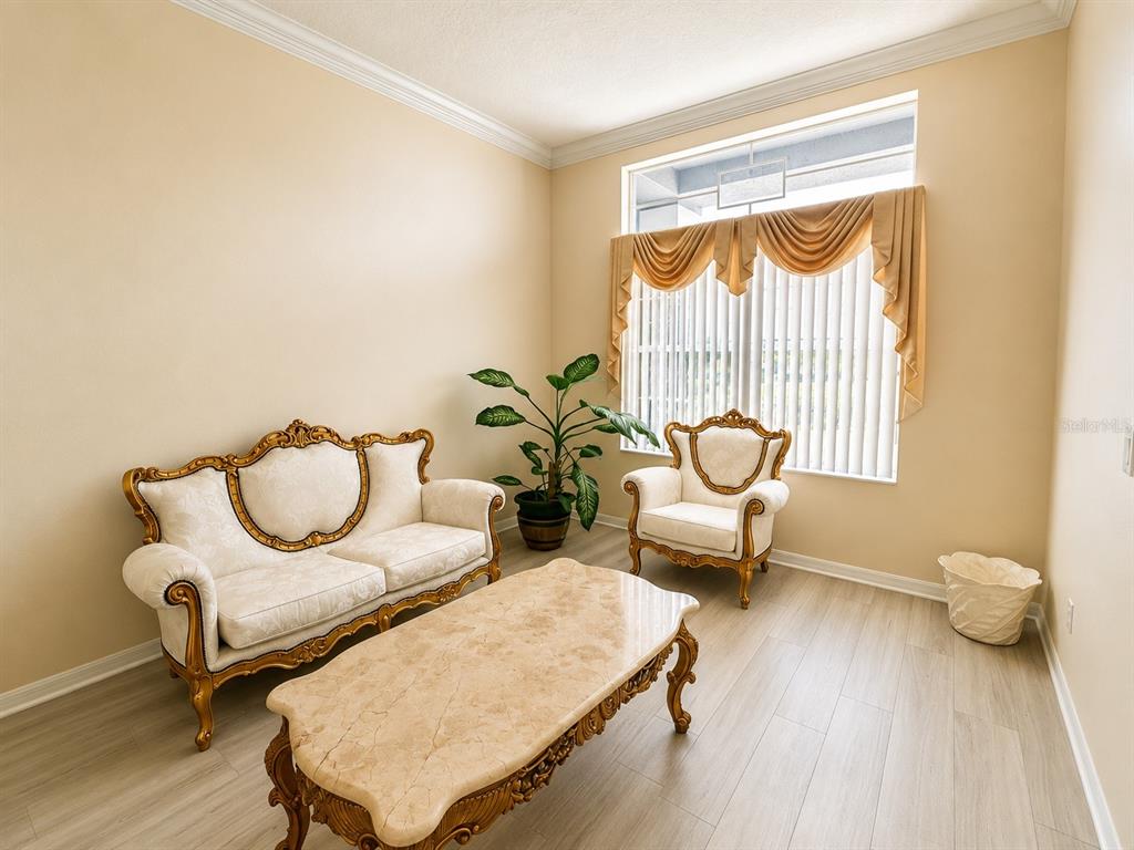 A formal living room features a sofa, armchair, coffee table, and a large window with valances — 13448 SUMMER RAIN DRIVE, ORLANDO, FL