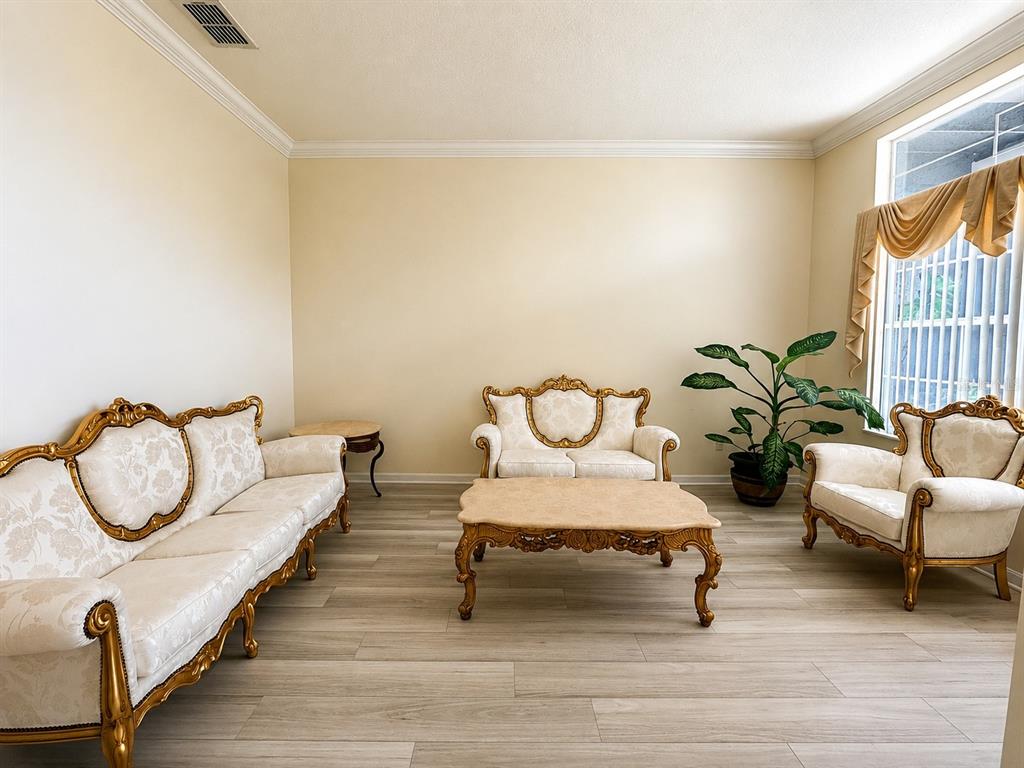 A living room features light wood-look flooring, cream walls, and a matching ornate furniture set — 13448 SUMMER RAIN DRIVE, ORLANDO, FL