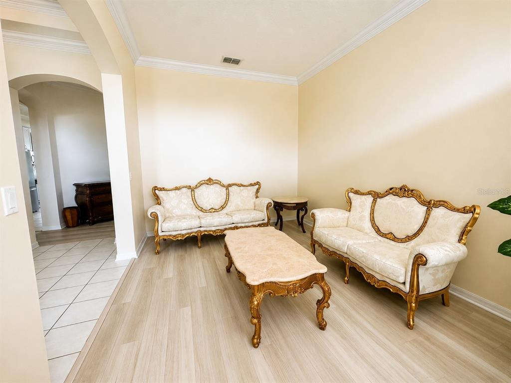 A living room features two ornate cream-colored sofas, a matching coffee table, and light wood flooring — 13448 SUMMER RAIN DRIVE, ORLANDO, FL
