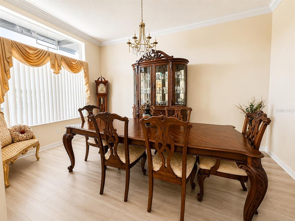 A dining room features a wooden table, matching chairs, a china cabinet, and light flooring — 13448 SUMMER RAIN DRIVE, ORLANDO, FL
