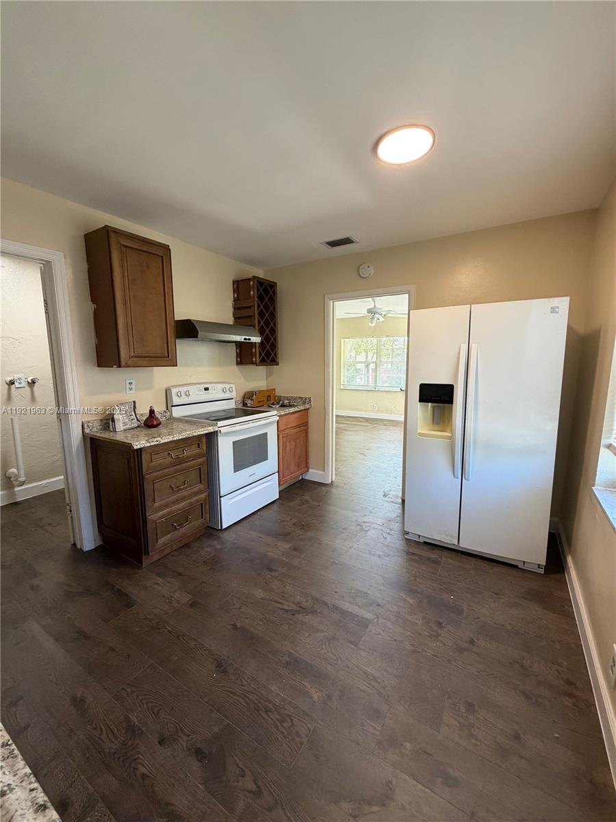 A kitchen features dark wood cabinets, granite countertops, white appliances, and dark wood-look flooring — 1320 SW 11th Ave # A, Deerfield Beach FL 33441, DEERFIELD BEACH, FL