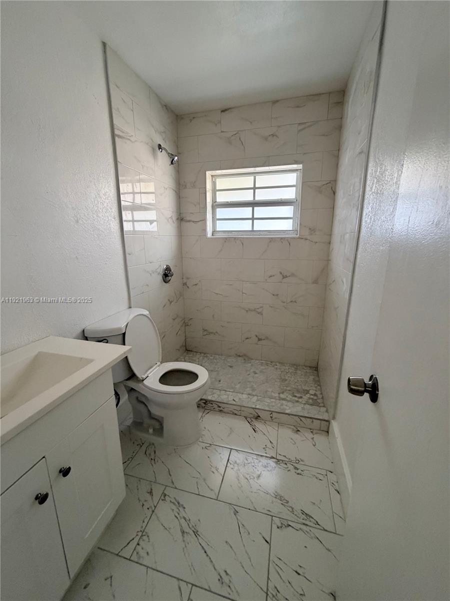 A bathroom features a white vanity, a toilet, and a tiled walk-in shower — 1320 SW 11th Ave # A, Deerfield Beach FL 33441, DEERFIELD BEACH, FL