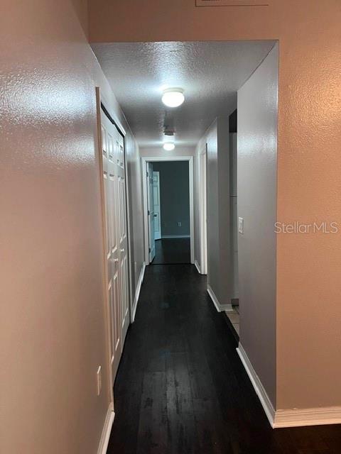 A hallway with dark wood-look flooring leads to a doorway in a residential interior — 1810 E PALM AVENUE UNIT 1117, TAMPA, FL